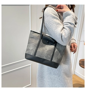 Detailed side view of grey marble-pattern canvas tote with black leather trim on model
