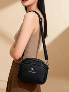 Détail de la sacoche noire en cuir PU multicouche avec logo kangourou argenté et fermeture