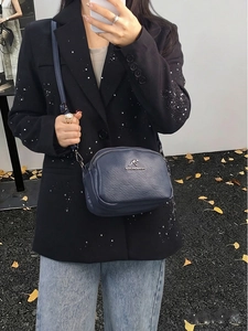 Détail du sac coquille bleu foncé en cuir grainé avec logo kangourou et plaque métal