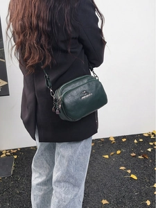 Détail du sac bandoulière vert foncé en cuir PU avec texture grainée et logo argent