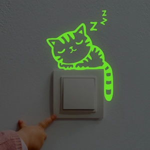 Luminous sleeping cat wall sticker glowing in the dark above a light switch