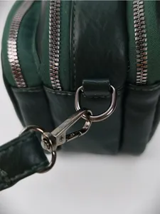 Détail du sac en cuir vert foncé à texture litchi avec crochet pivotant en métal noir