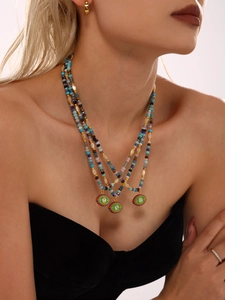 Macro detail of layered beaded necklace with evil eye pendant and natural stones