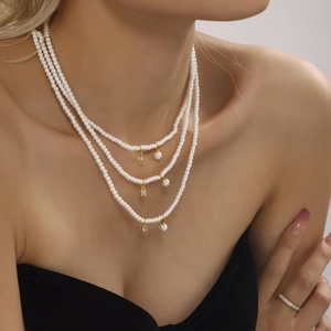 Three-layer pearl choker necklace with gold heart zircon pendants on a female model