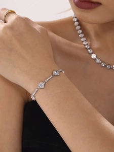 Nahaufnahme eines silbernen Armbands mit drei herzförmigen Zirkoniasteinen am Handgelenk