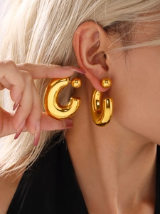 Close-up of polished 18K gold-plated C-shaped hollow hoop earrings with a spherical stud