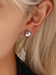 Macro shot of minimalist high-polished silver steel ball stud earring on ear model