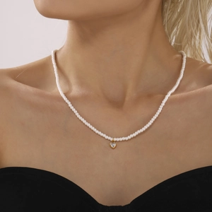 Elegante girocollo di perle con ciondolo a cuore in zircone dorato indossato da donna