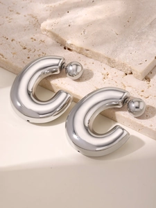 Detailed close-up of C-shaped polished steel stud earrings on natural stone background