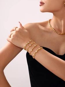 Detail of stacked 18K gold plated bracelets and rings with geometric cubic zirconia