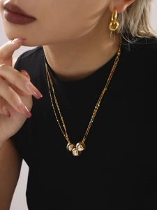Detail of layered gold beaded necklace and matching interlocking hoop earrings on model