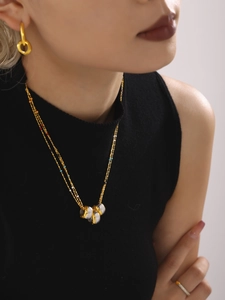Detail of layered gold necklace with colorful beads and two-tone cylindrical pendants