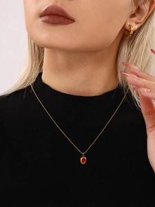 Detail van model met gouden ketting met rode steen en pavé oorringen met zirkonia steentjes
