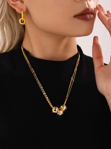 Close-up of triple-layer mixed metal necklace with colorful beads and gold earrings