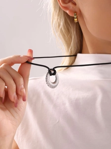 Primer plano del colgante redondo de plata texturizada en cordón negro para jersey