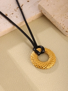 Primer plano de colgante dorado con textura de rombos y cordón negro