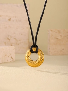 Detalle del colgante redondo dorado con relieve de diamantes en cordón negro fino