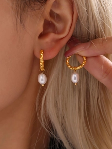 Close-up of gold twist texture hoop earrings with teardrop freshwater pearl pendants