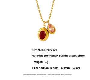 Detail van vergulde kogelketting met rode ovale en roze druppelvormige zirkoonhanger
