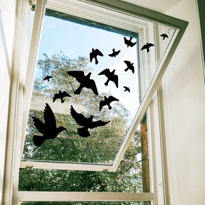 Detailed view of black bird silhouette decals applied to a glass window with a garden view