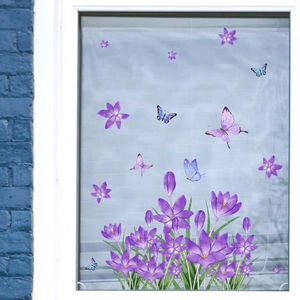 Detail of purple crocus flowers and colorful butterfly window stickers on a glass pane