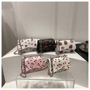 Mini chain crossbody bags with cute strawberry and cherry prints on white display stands