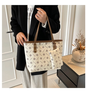 Detailed shot of beige printed tote bag with brown clover pattern and small pouch