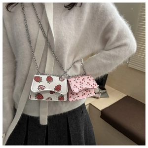 Close-up of strawberry and cherry print crossbody bags with silver chain straps