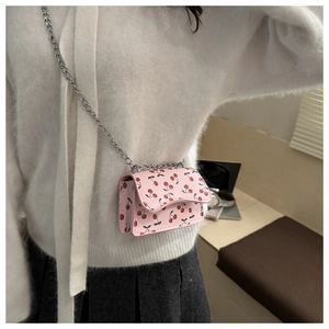 Detail der rosa Mini-Umhängetasche mit Kirschprint und silberner Kette am Modell