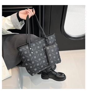 Detail view of black leather tote bag set with clover print and matching pouch