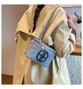Detail of blue glitter camera bag featuring a black double B logo and silver chain strap