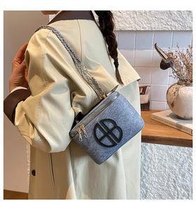Detail of blue denim mini square bag with leather B logo and gold chain strap on model