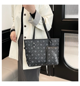 Close-up of black leather tote bag featuring repeating clover patterns and silver studs