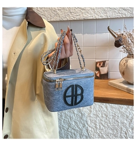 Close-up of blue textured vanity bag with gold chain strap and circular geometric logo