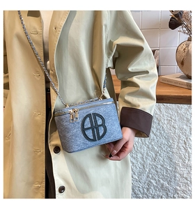 Detail of light blue tweed box bag with gold chain strap and circular metal logo