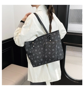 Detail of a large black monogram tote bag set with matching coin purse and gold rivets