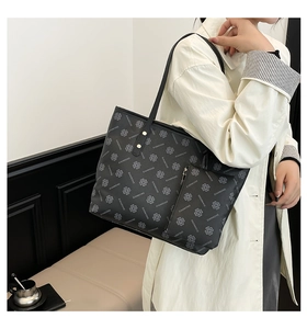Side view of large black tote bag with white clover patterns and matching coin purse