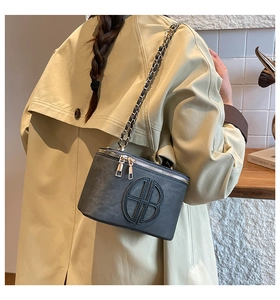 Detail of grey crossbody bag with vintage embossed logo and metal chain shoulder strap