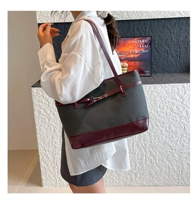 Détail du tissu tissé gris et de la bandoulière en cuir bordeaux du sac à bandoulière