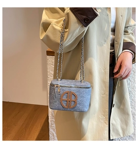 Petit sac bandoulière bleu texture denim avec logo doré et chaîne porté par un modèle