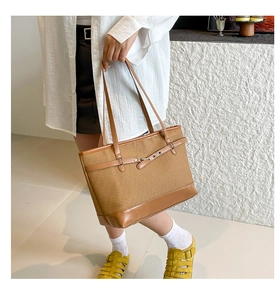 Détail d'un grand sac cabas tissé marron avec finitions cuir et boucle métallique