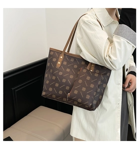 Brown tote bag with clover pattern and small zipper pouch shown on a model side view
