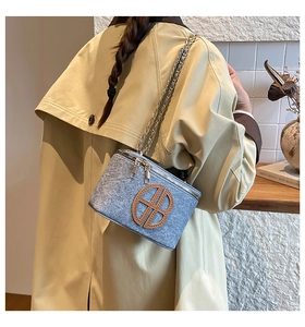 Detail of blue tweed shoulder bag with brown leather logo and gold chain strap