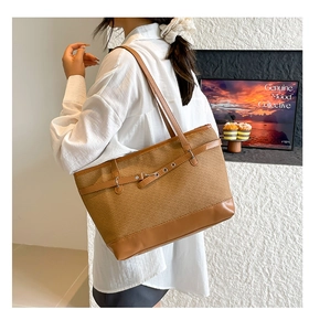 Détail d'un sac cabas marron tissé avec lanières en cuir et boucle décorative élégante