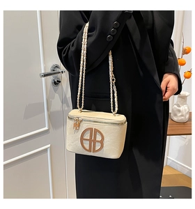 Detailed view of cream box bag with BB logo and chain strap on chic black blazer