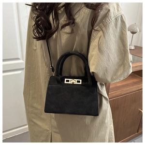 Dettaglio della borsa in pelle scamosciata nera con chiusura girevole dorata e texture