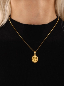 Close-up of a layered gold Virgin Mary pendant necklace worn over a black sweater