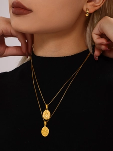 Close-up of double-layered gold religious pendant necklace and hoop earrings on model