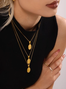 Detailed view of triple-layered gold necklaces with religious pendants and box chains