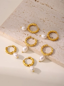 Detailed view of three gold-plated twist hoop earrings with white freshwater pearl drops